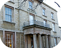 The main entrance of Peterborough Museum, a 19th century, which features a balcony and pillars at the front. 
