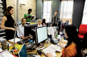 Busy office environment, with people working at computers in a modern, stylish office