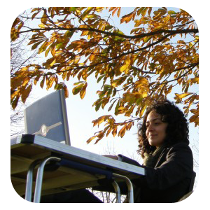 A lady working on her laptop outside, under a horse chesnut tree